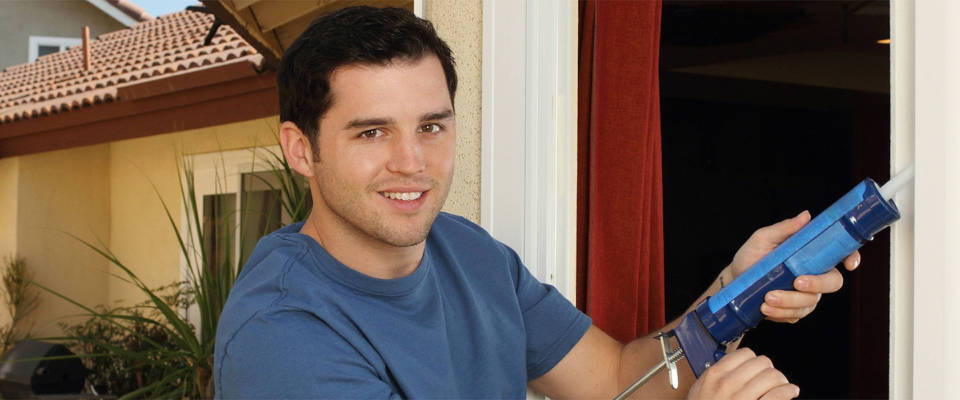 Energy-Saving-Tips Man caulking around door frames