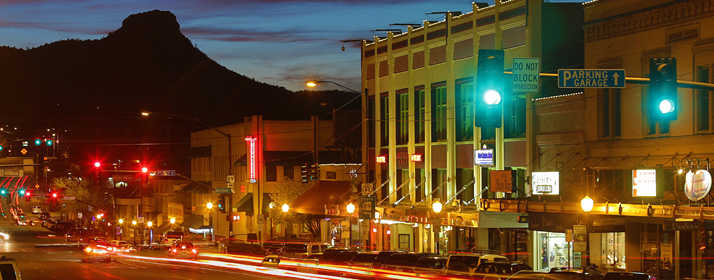 Downtown Prescott, AZ with Thumb Butte at the left, comes to light as the sun sets.